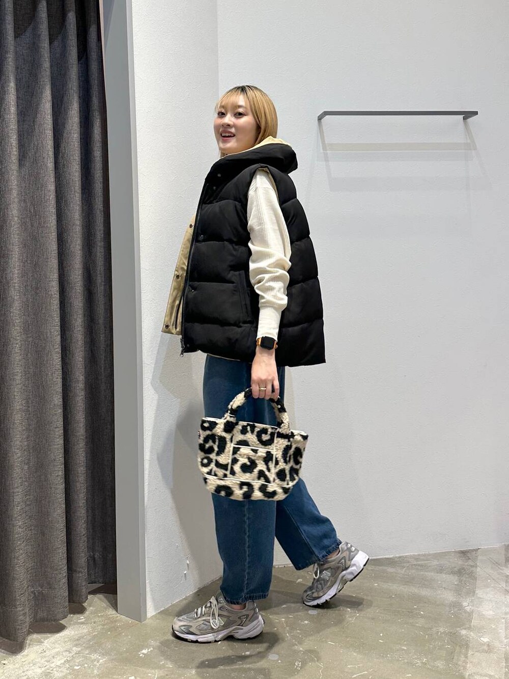 ベージュ系のトートバッグ、ブラック系のベスト、ホワイト系のTシャツ/カットソーを着用したレディースの秋コーディネートの2枚目の写真