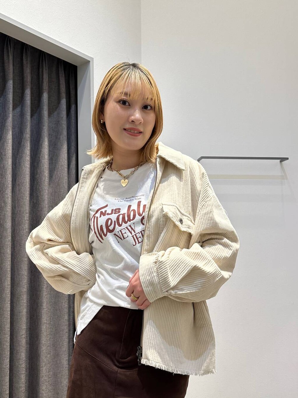 ブラウン系のスカート、ホワイト系のTシャツ/カットソー、ホワイト系のブルゾンを着用したレディースの秋コーディネートの8枚目の写真