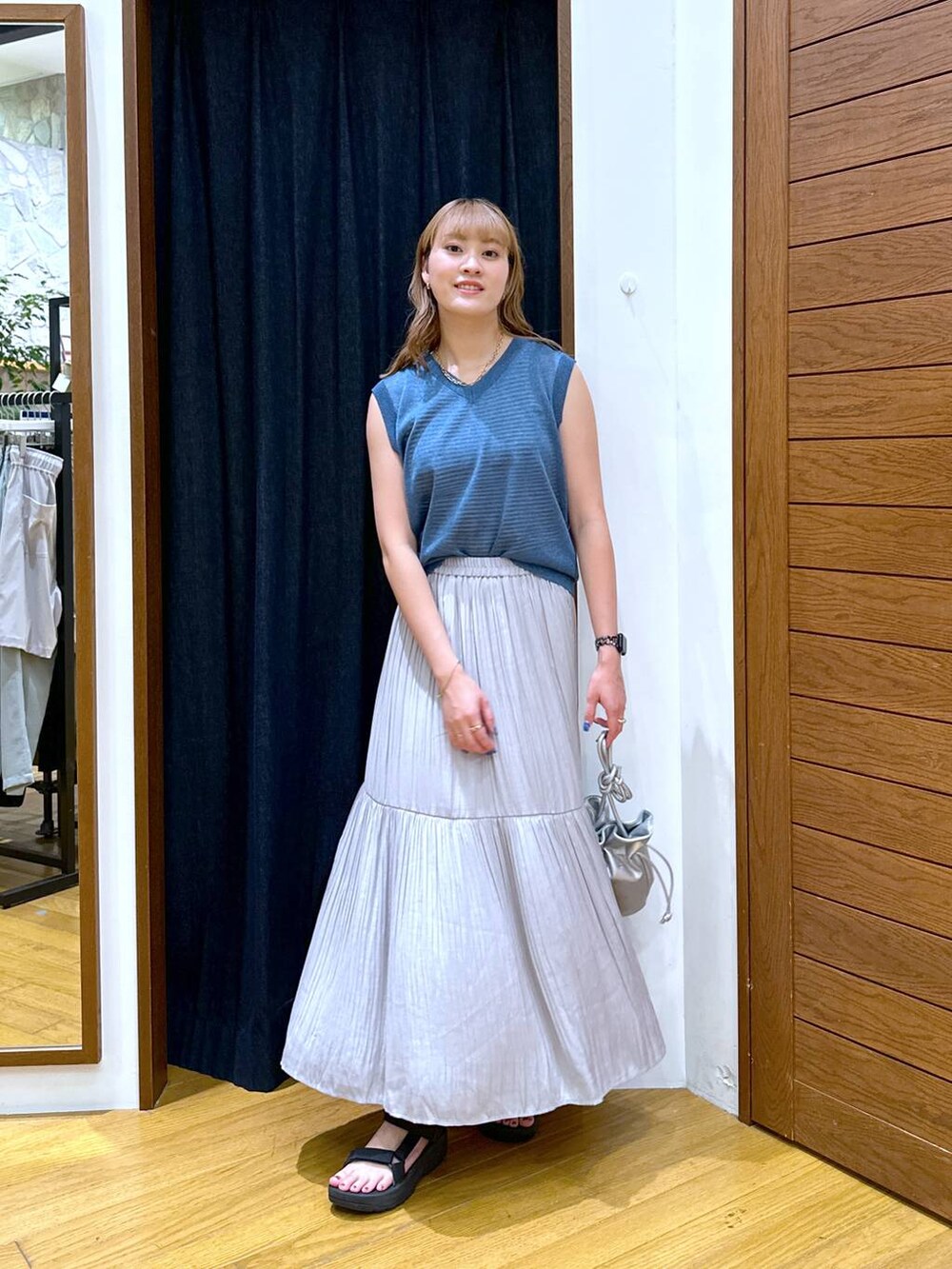 ブルー系のベスト、ブラック系のサンダル、グレー系のスカートを着用したレディースの夏コーディネートの4枚目の写真