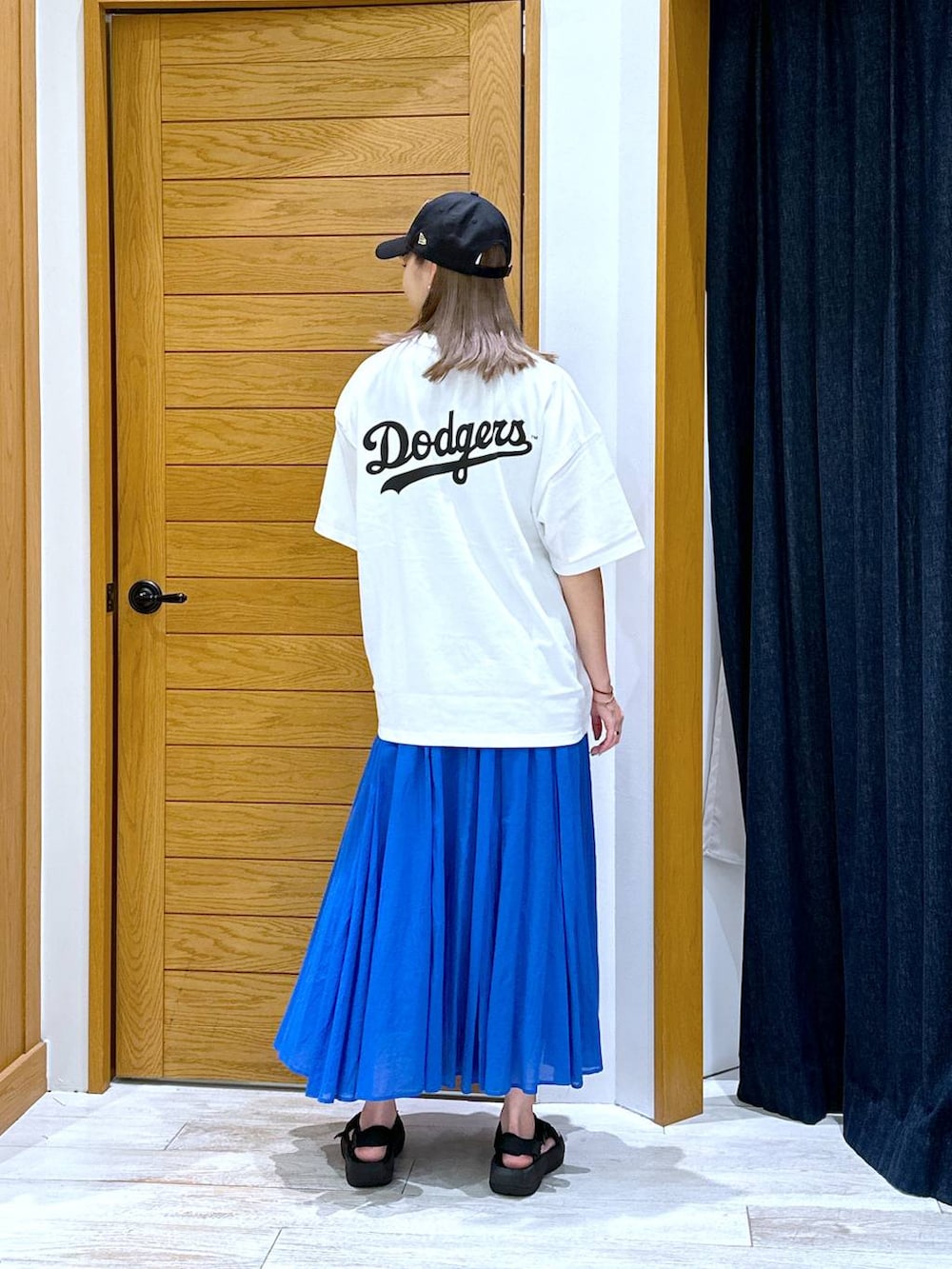 ブルー系のスカート、ブラック系のサンダル、ホワイト系のTシャツ/カットソーを着用したレディースの夏コーディネートの3枚目の写真