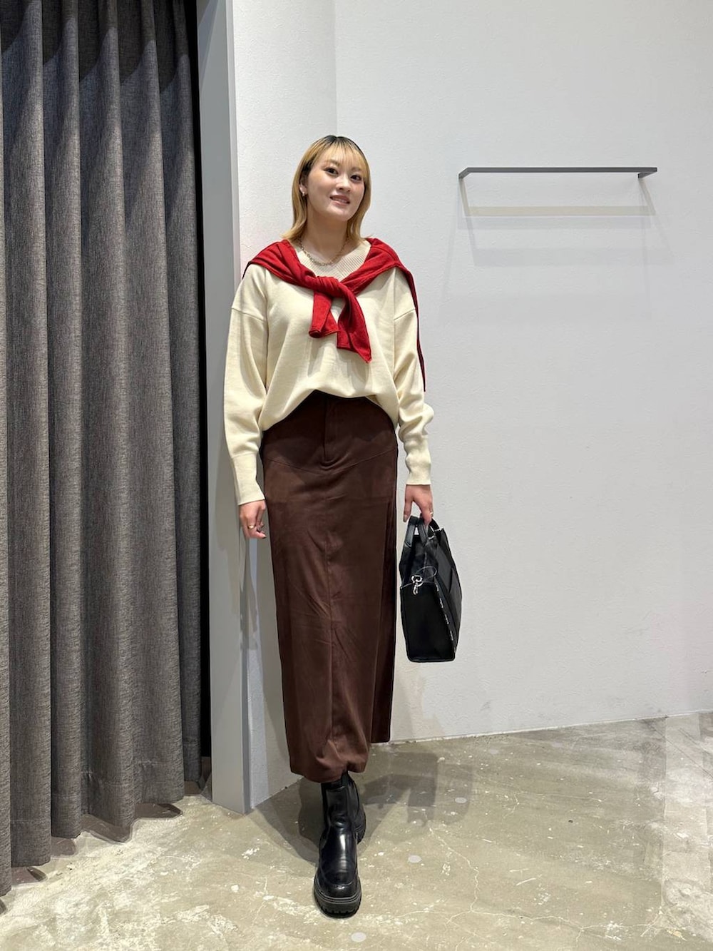 ブラウン系のスカート、ホワイト系のニット/セーター、ブラック系のトートバッグを着用したレディースの秋コーディネートの8枚目の写真