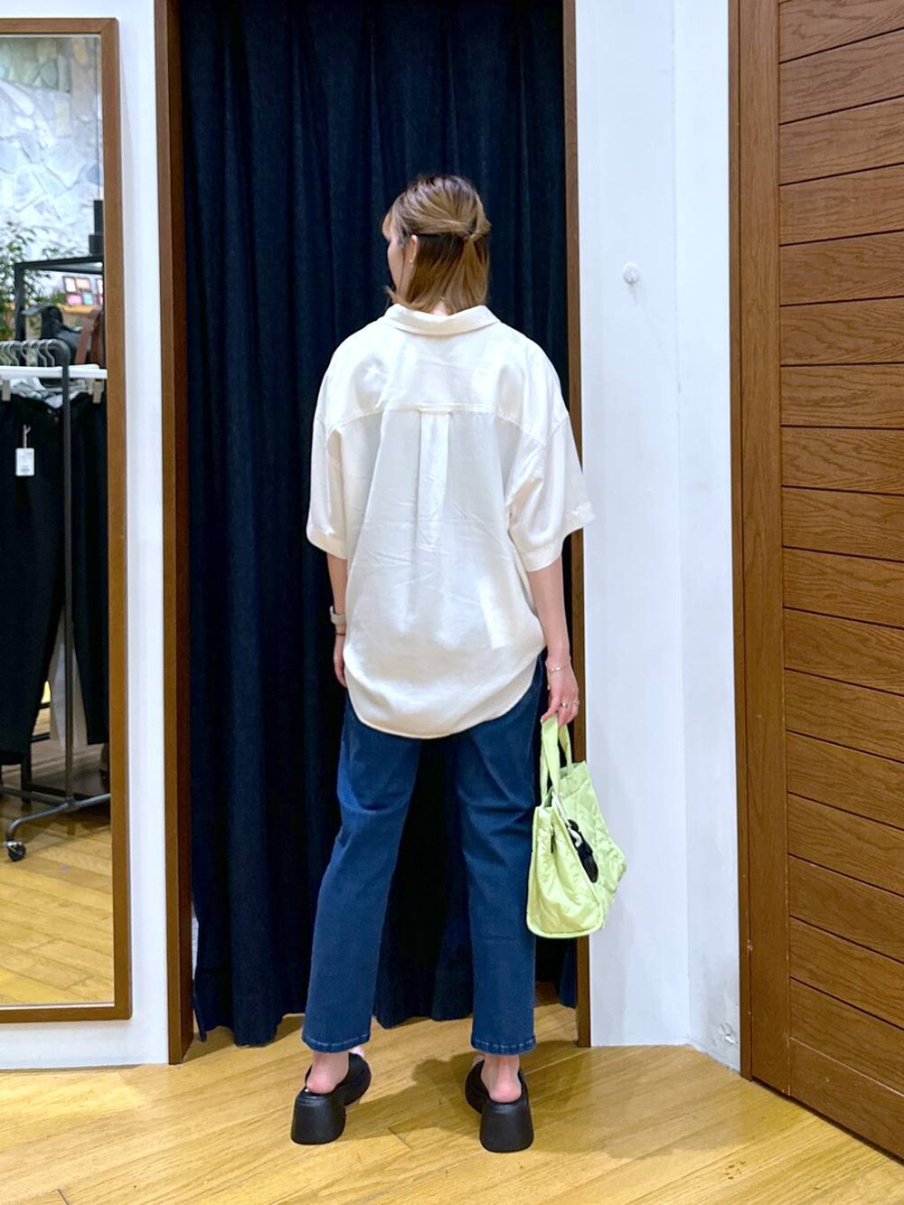 ブラック系のサンダル、ブルー系のデニムパンツ、グリーン系のトートバッグを着用したレディースの夏コーディネートの3枚目の写真