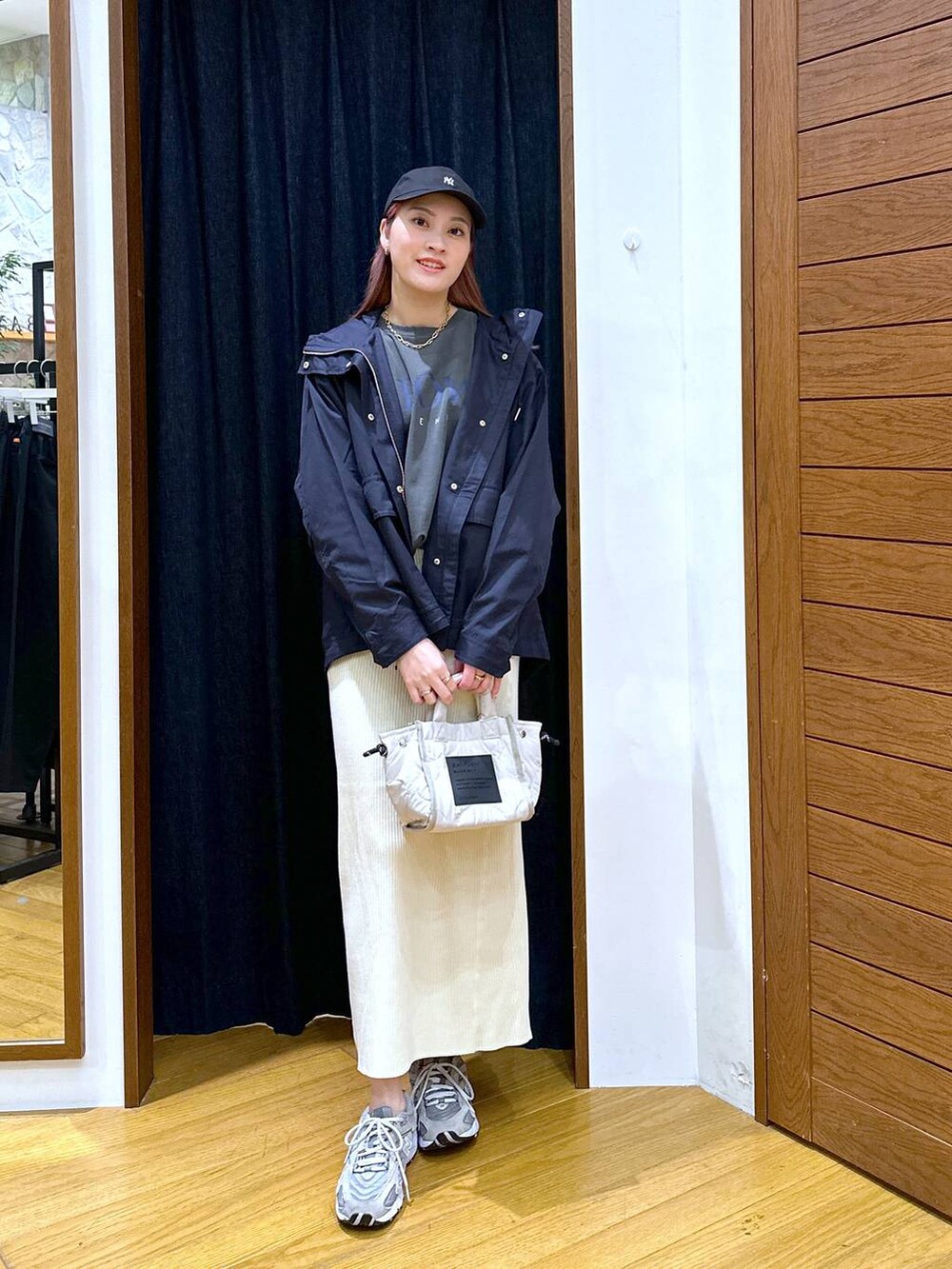 ベージュ系のスカート、ブルー系のマウンテンパーカー、ホワイト系のショルダーバッグを着用したレディースの秋コーディネートの4枚目の写真
