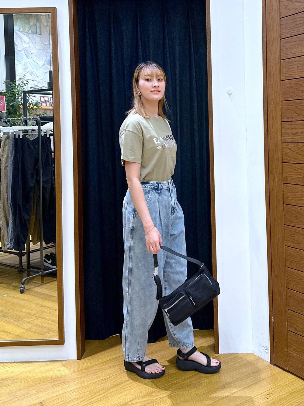 ブラック系のショルダーバッグ、グリーン系のTシャツ/カットソー、ブラック系のサンダルを着用したレディースの夏コーディネートの2枚目の写真