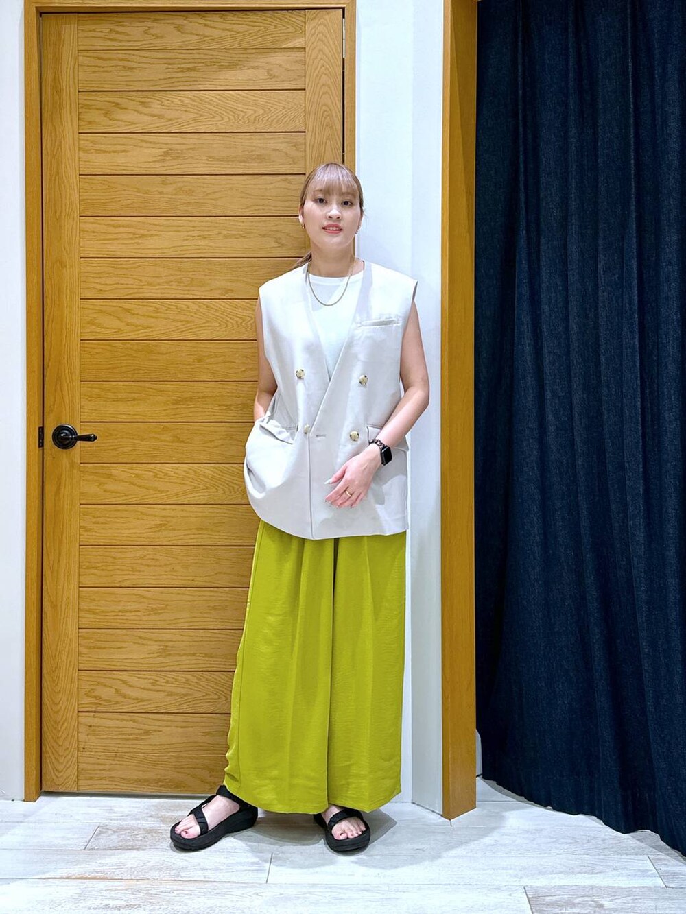 ホワイト系のTシャツ/カットソー、ベージュ系のベスト、ブラック系のサンダルを着用したレディースの夏コーディネートの4枚目の写真