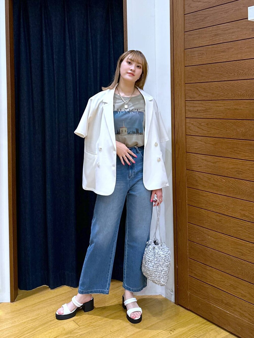 シルバー系のハンドバッグ、ホワイト系のテーラードジャケット、ブルー系のデニムパンツを着用したレディースの夏コーディネートの4枚目の写真