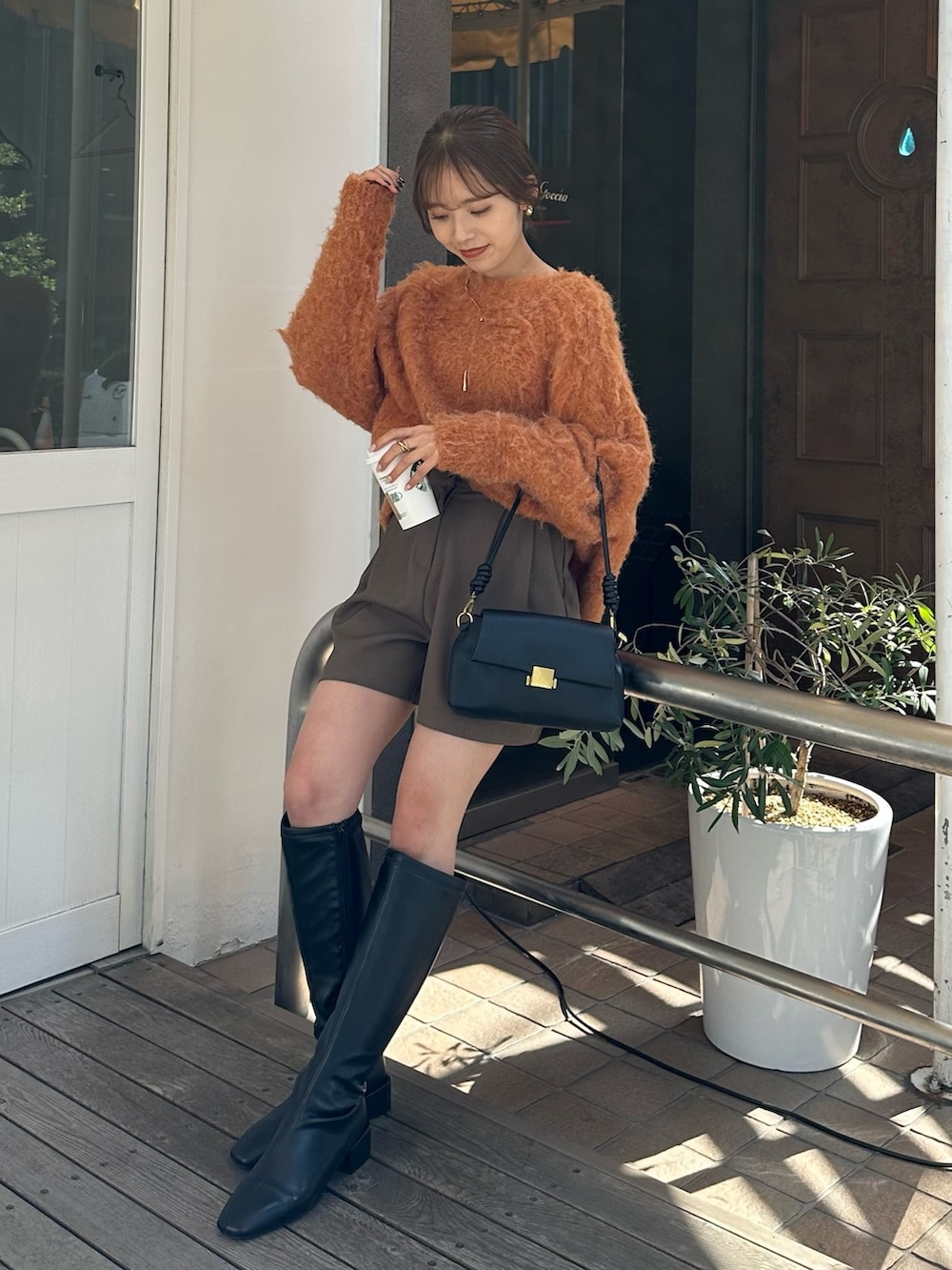 ブラック系のブーツ、オレンジ系のニット/セーター、グリーン系のその他パンツを着用したレディースの秋コーディネートの5枚目の写真