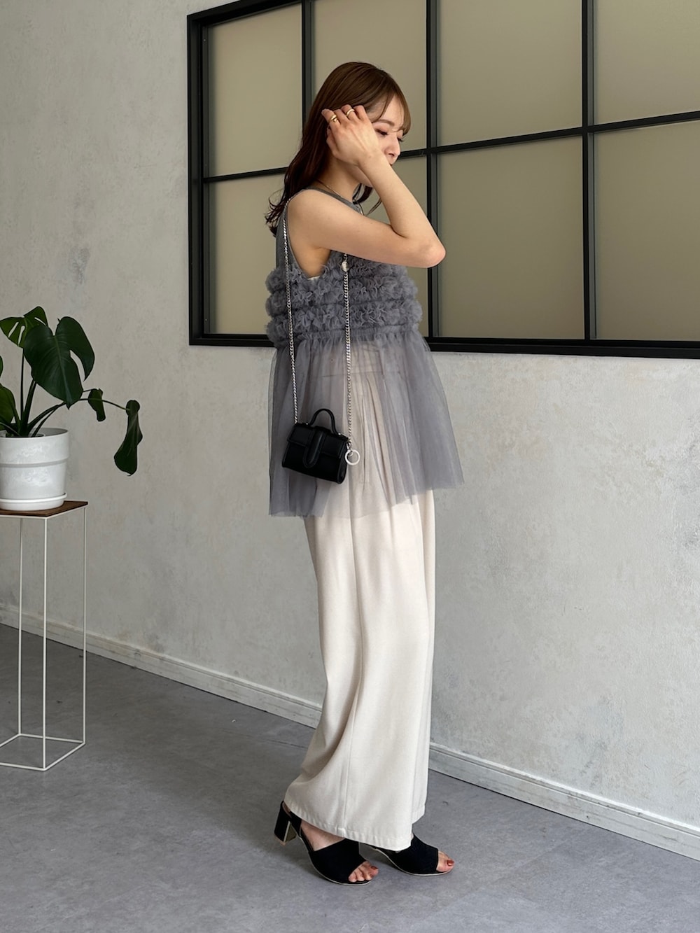 グレー系のTシャツ/カットソー、ホワイト系のスラックス、ブラック系のサンダルを着用したレディースの春コーディネートの4枚目の写真