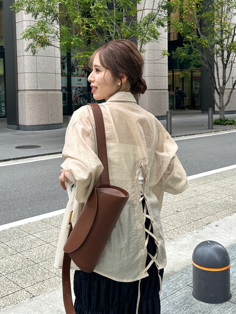 ブラック系のスカート、ベージュ系のシャツ/ブラウス、ブラウン系のショルダーバッグを着用したレディースの春コーディネートの2枚目の写真