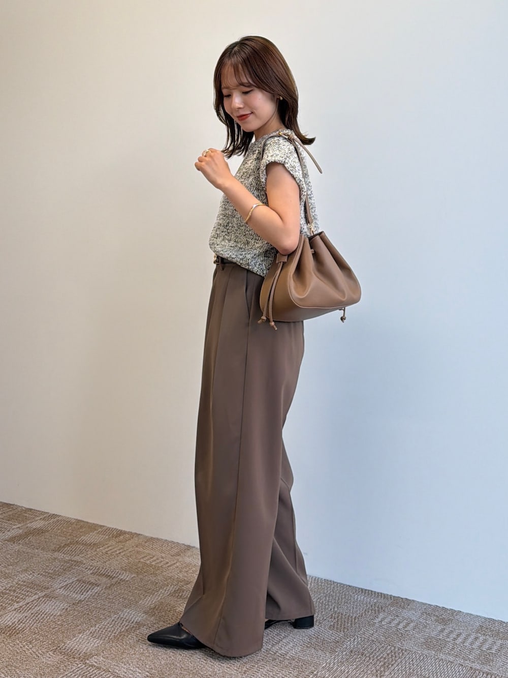 ベージュ系のニット/セーター、ブラック系のパンプス、ブラウン系のスラックスを着用したレディースの夏コーディネートの2枚目の写真