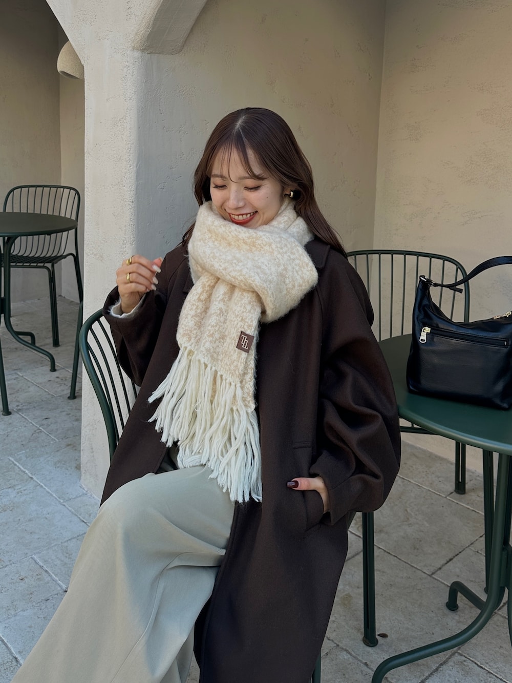 ブラウン系のその他アウター、ベージュ系のスラックス、ホワイト系のニット/セーターを着用したレディースの冬コーディネートの5枚目の写真