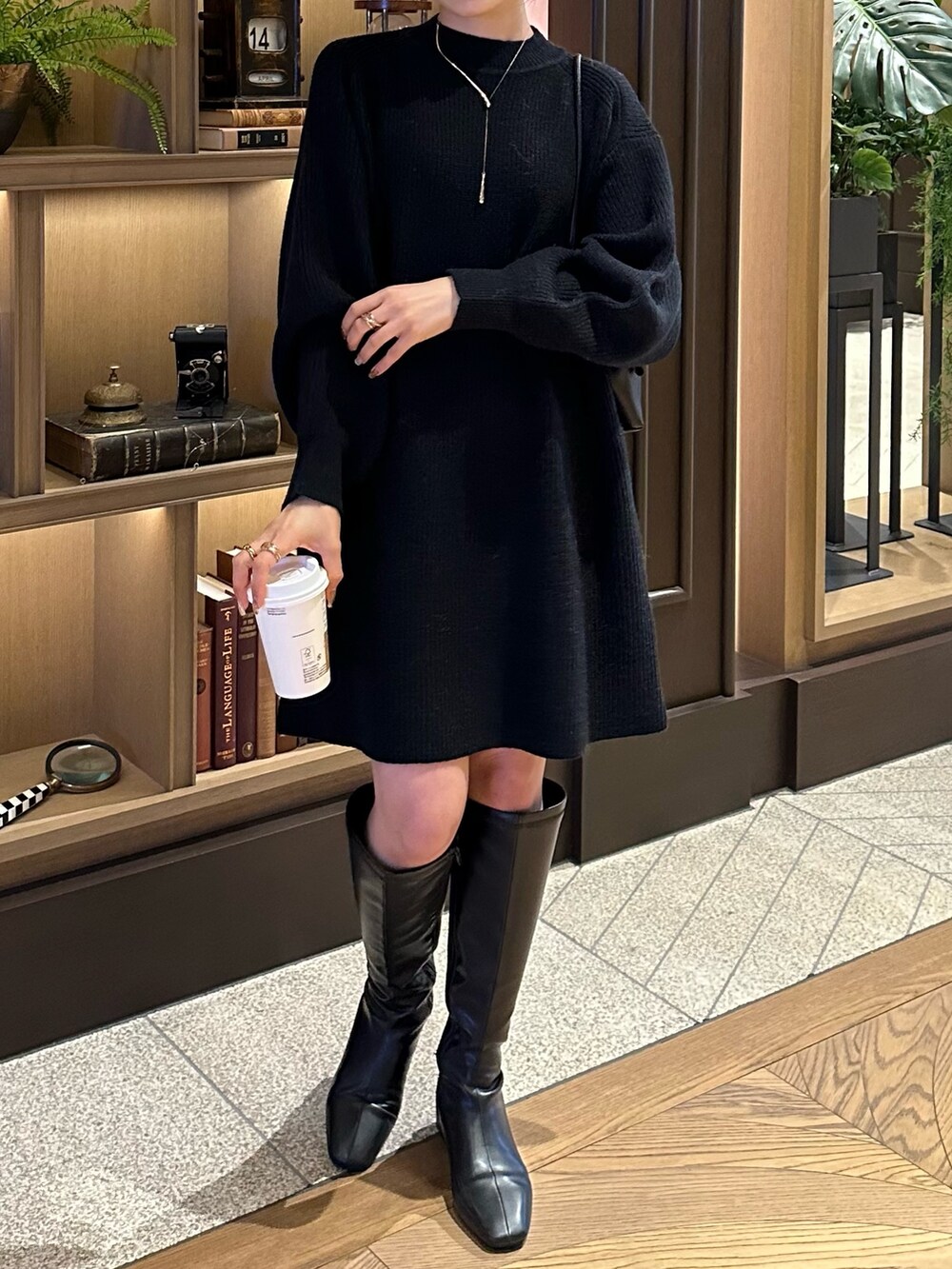 ベージュ系のノーカラーコート、ブラック系のワンピース、ブラック系のブーツを着用したレディースの秋コーディネートの3枚目の写真