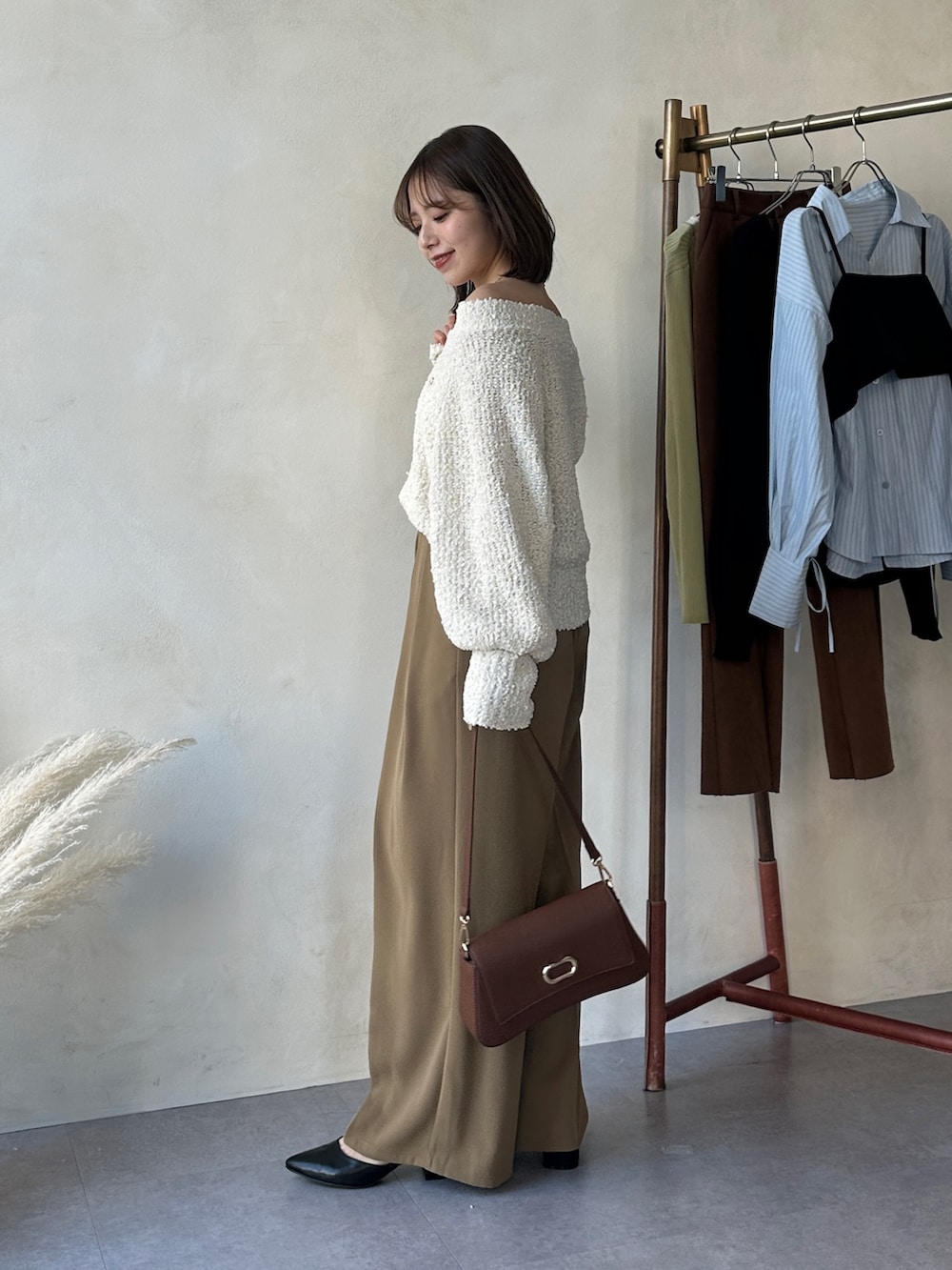 イエロー系のスラックス、ブラック系のパンプス、ホワイト系のニット/セーターを着用したレディースの冬コーディネートの2枚目の写真