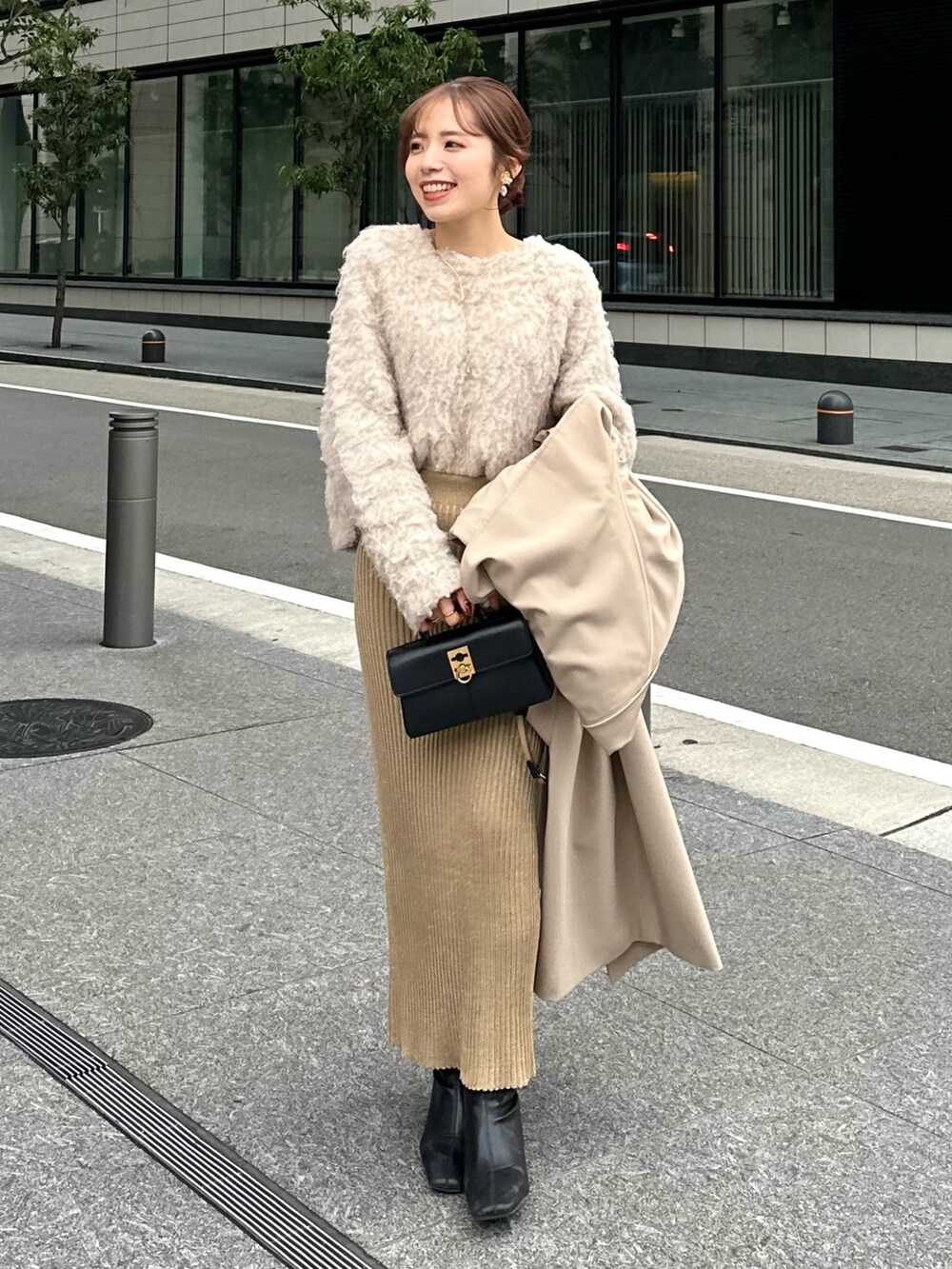 ベージュ系のステンカラーコート、ベージュ系のニット/セーター、ベージュ系のスカートを着用したレディースの冬コーディネートの2枚目の写真