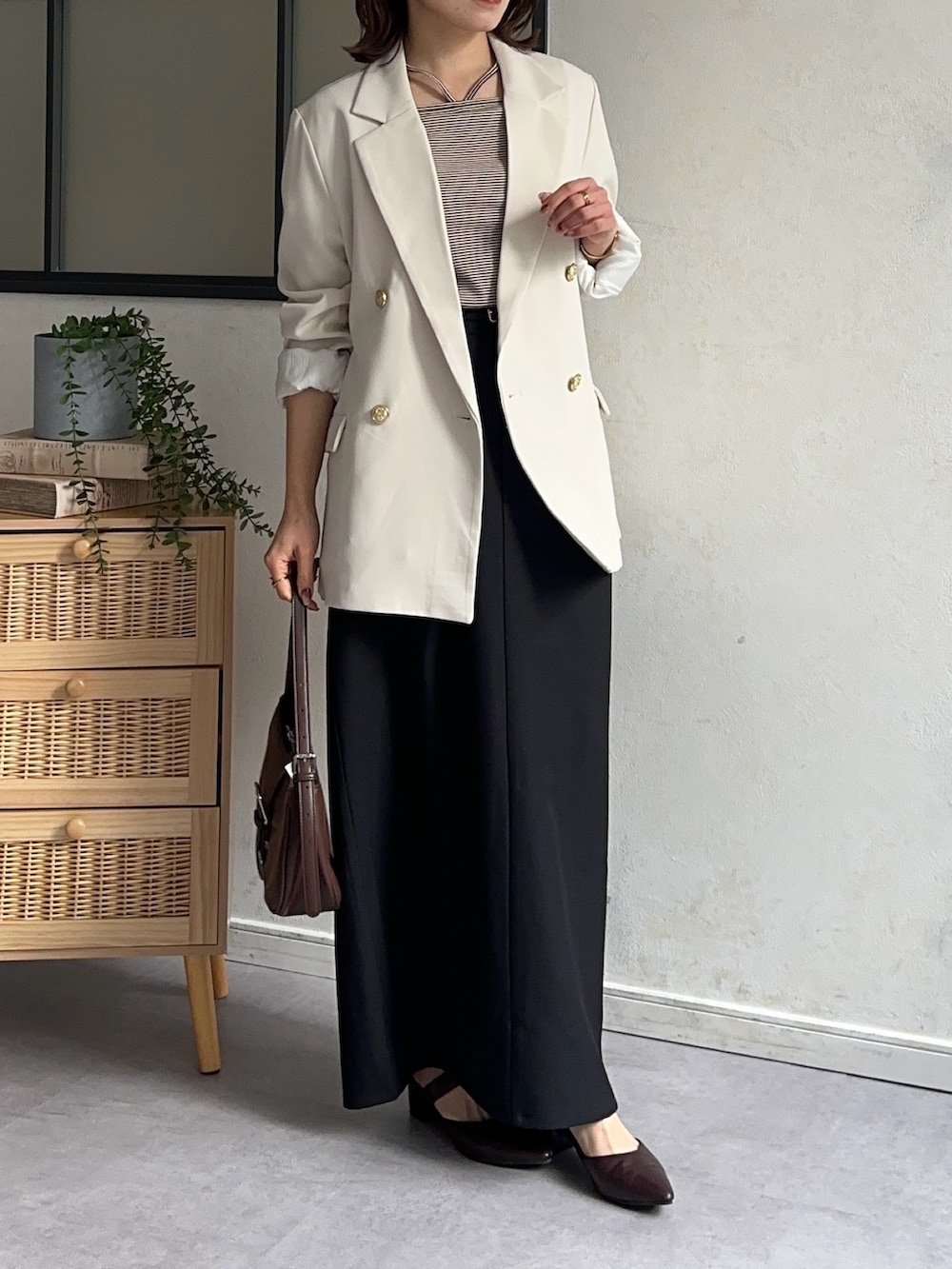 ホワイト系のテーラードジャケット、ブラック系のスカート、ブラウン系のパンプスを着用したレディースの冬コーディネートの4枚目の写真