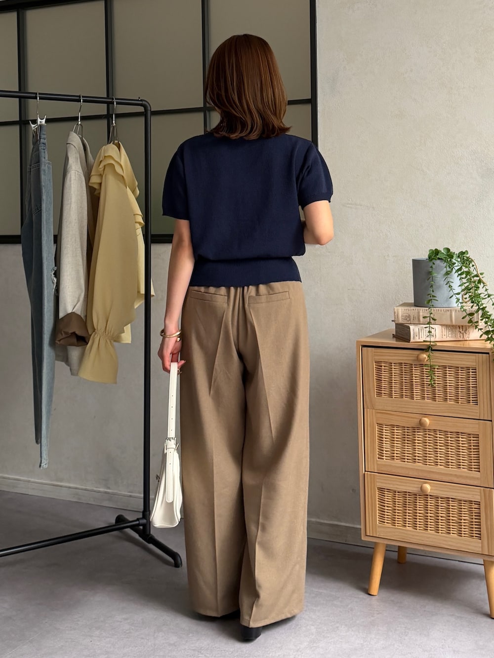 ブラウン系のスラックス、ブルー系のカーディガン/ボレロ、ブラック系のパンプスを着用したレディースの春コーディネートの3枚目の写真