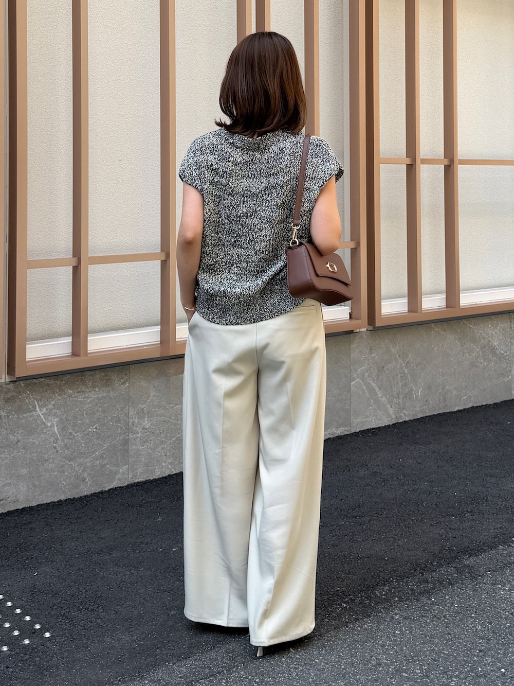 ホワイト系のスラックス、ブラック系のニット/セーター、ブラウン系のパンプスを着用したレディースの春コーディネートの4枚目の写真