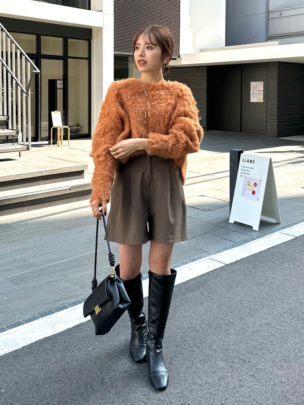 ブラック系のブーツ、オレンジ系のニット/セーター、グリーン系のその他パンツを着用したレディースの秋コーディネートの3枚目の写真