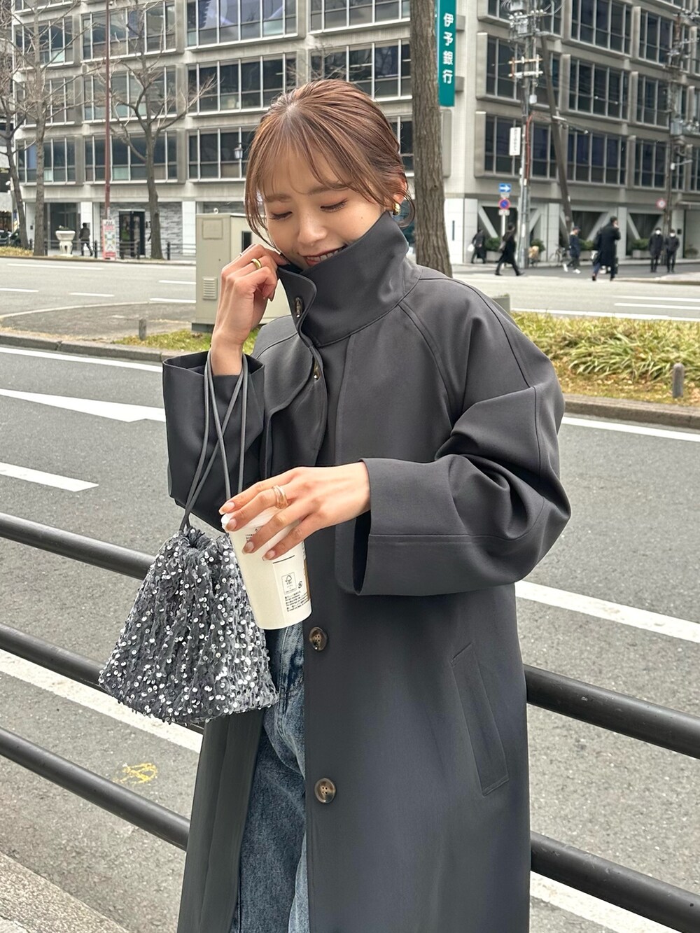 ブルー系のデニムパンツ、グレー系のトートバッグ、グレー系のステンカラーコートを着用したレディースの冬コーディネートの5枚目の写真