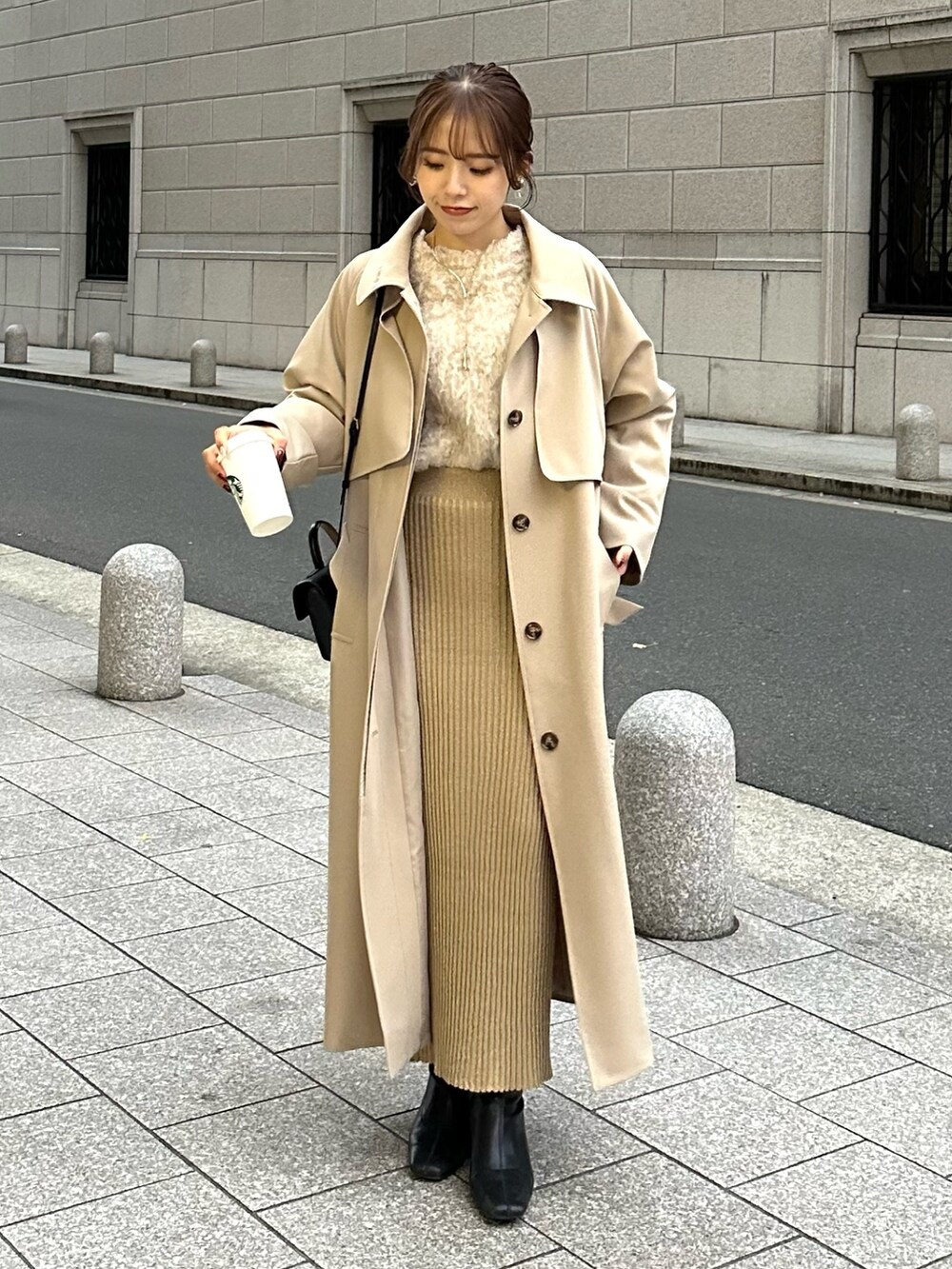 ベージュ系のステンカラーコート、ベージュ系のニット/セーター、ベージュ系のスカートを着用したレディースの冬コーディネートの4枚目の写真