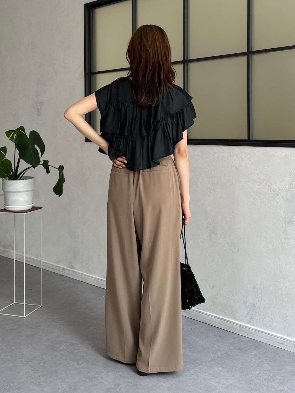 ブラック系のシャツ/ブラウス、ベージュ系のスラックス、ブラック系のトートバッグを着用したレディースの春コーディネートの2枚目の写真