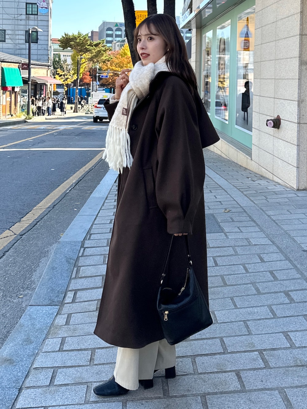 ブラウン系のその他アウター、ベージュ系のスラックス、ホワイト系のニット/セーターを着用したレディースの冬コーディネートの7枚目の写真