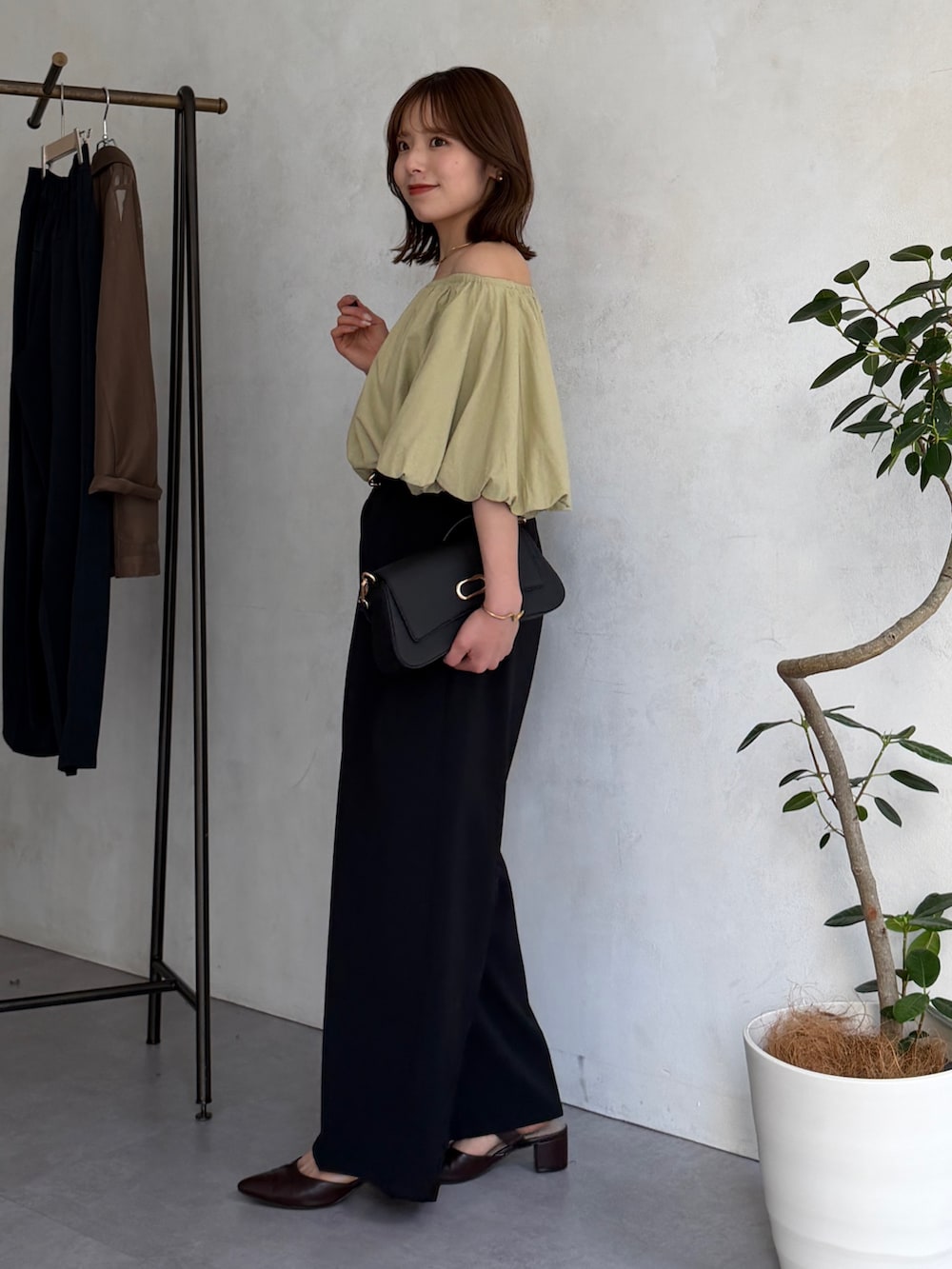 ブラック系のスラックス、イエロー系のシャツ/ブラウス、ブラウン系のパンプスを着用したレディースの春コーディネートの2枚目の写真