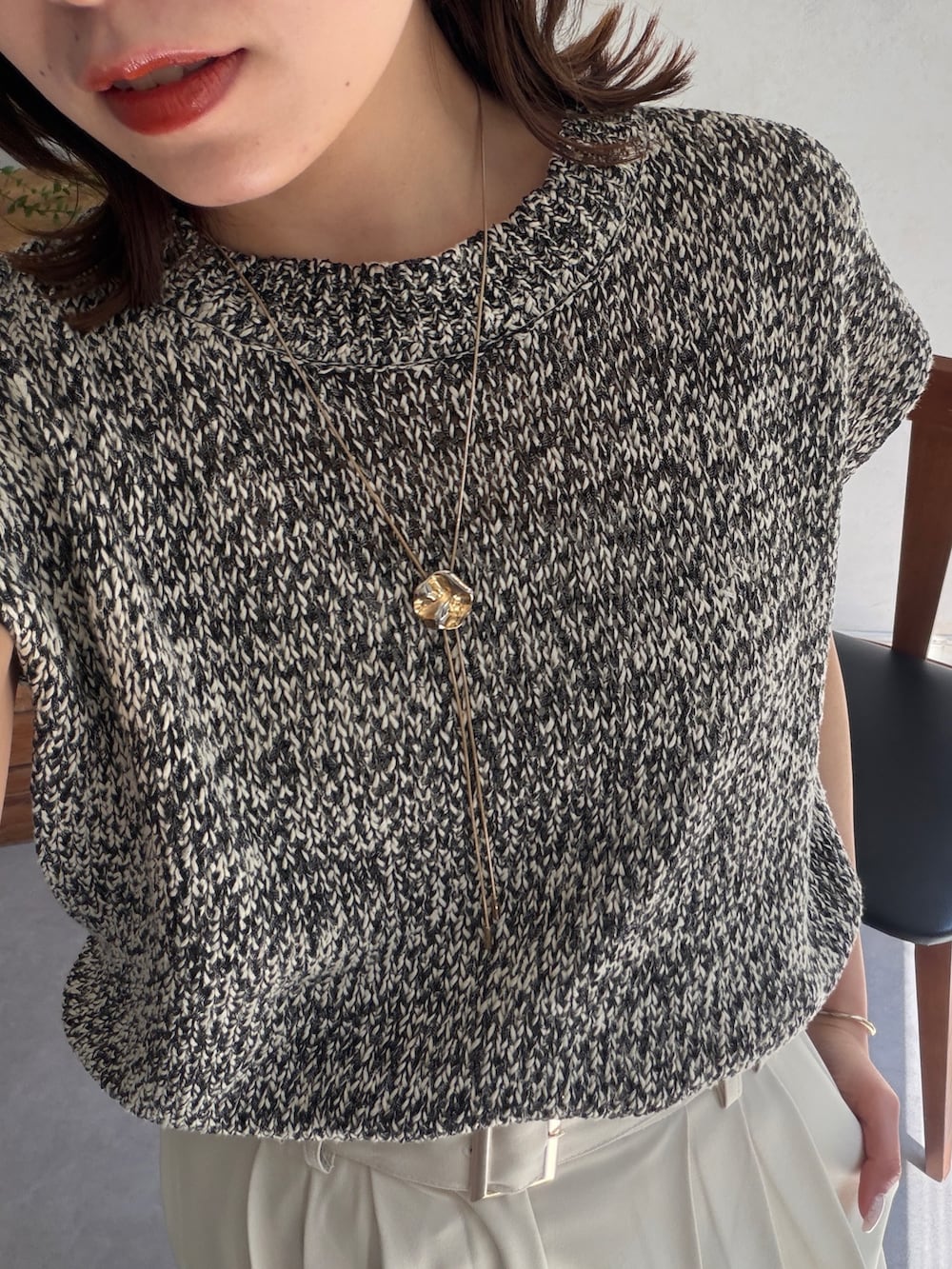 ホワイト系のスラックス、ブラック系のニット/セーター、ブラウン系のパンプスを着用したレディースの春コーディネートの2枚目の写真