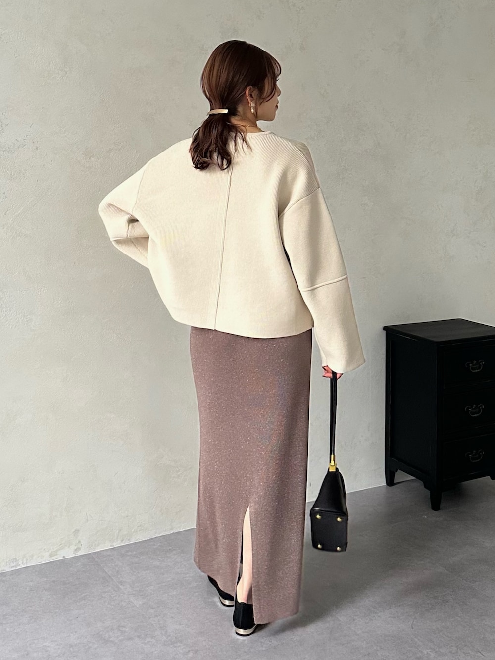 ブラウン系のスカート、ブラック系のパンプス、ホワイト系のカーディガン/ボレロを着用したレディースの冬コーディネートの2枚目の写真