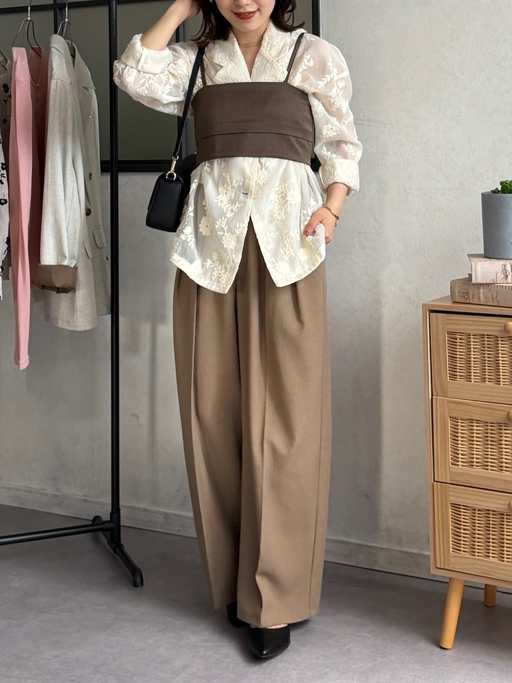 ブラウン系のスラックス、ブラック系のパンプス、ホワイト系のテーラードジャケットを着用したレディースの春コーディネートの2枚目の写真