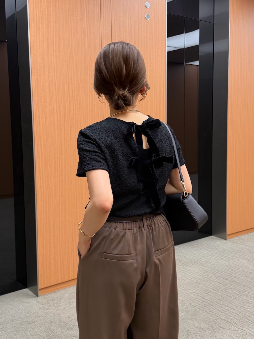 ブラウン系のスラックス、ブラック系のTシャツ/カットソー、ブラック系のベルトを着用したレディースの夏コーディネートの2枚目の写真