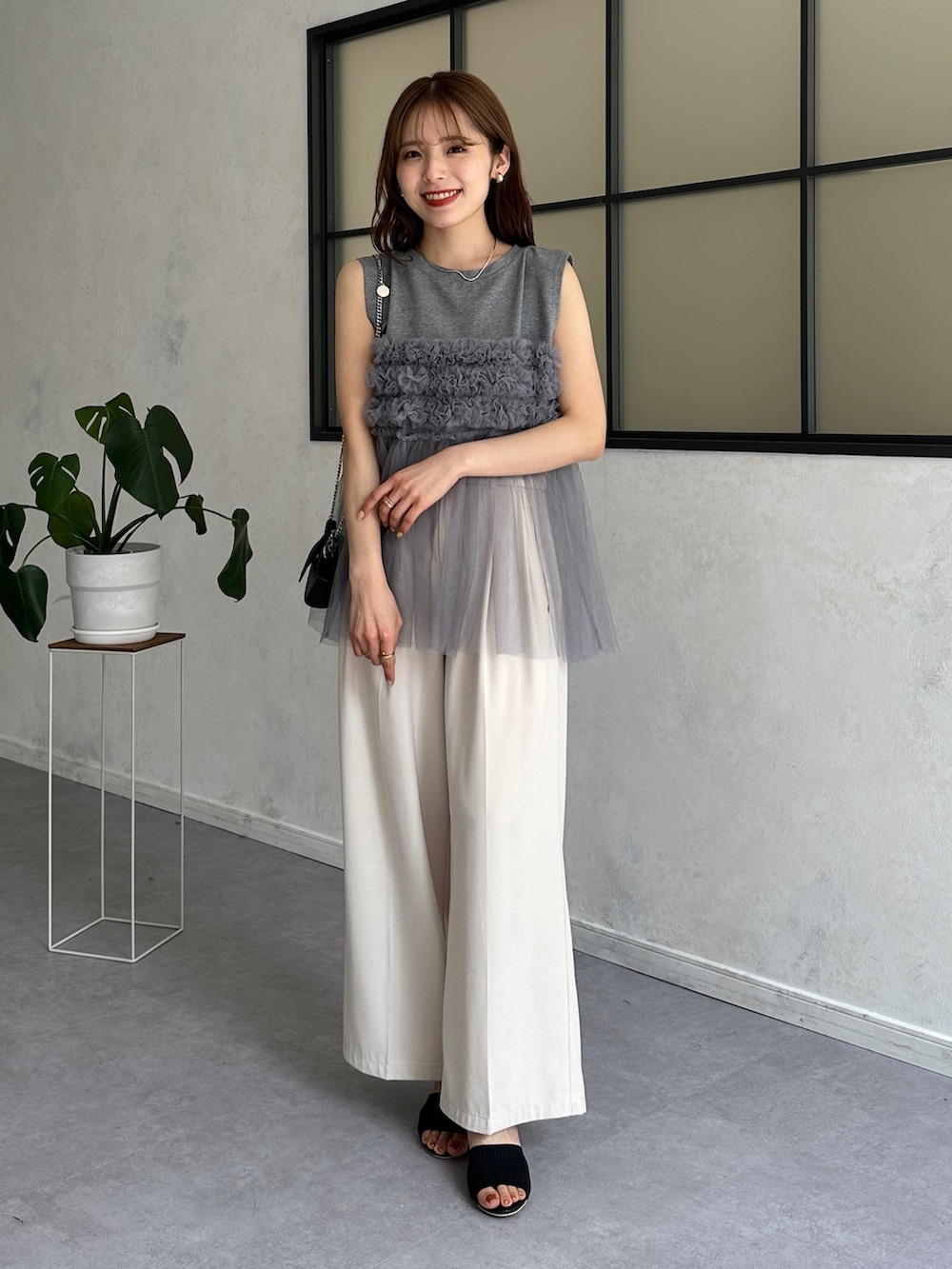 グレー系のTシャツ/カットソー、ホワイト系のスラックス、ブラック系のサンダルを着用したレディースの春コーディネートの5枚目の写真