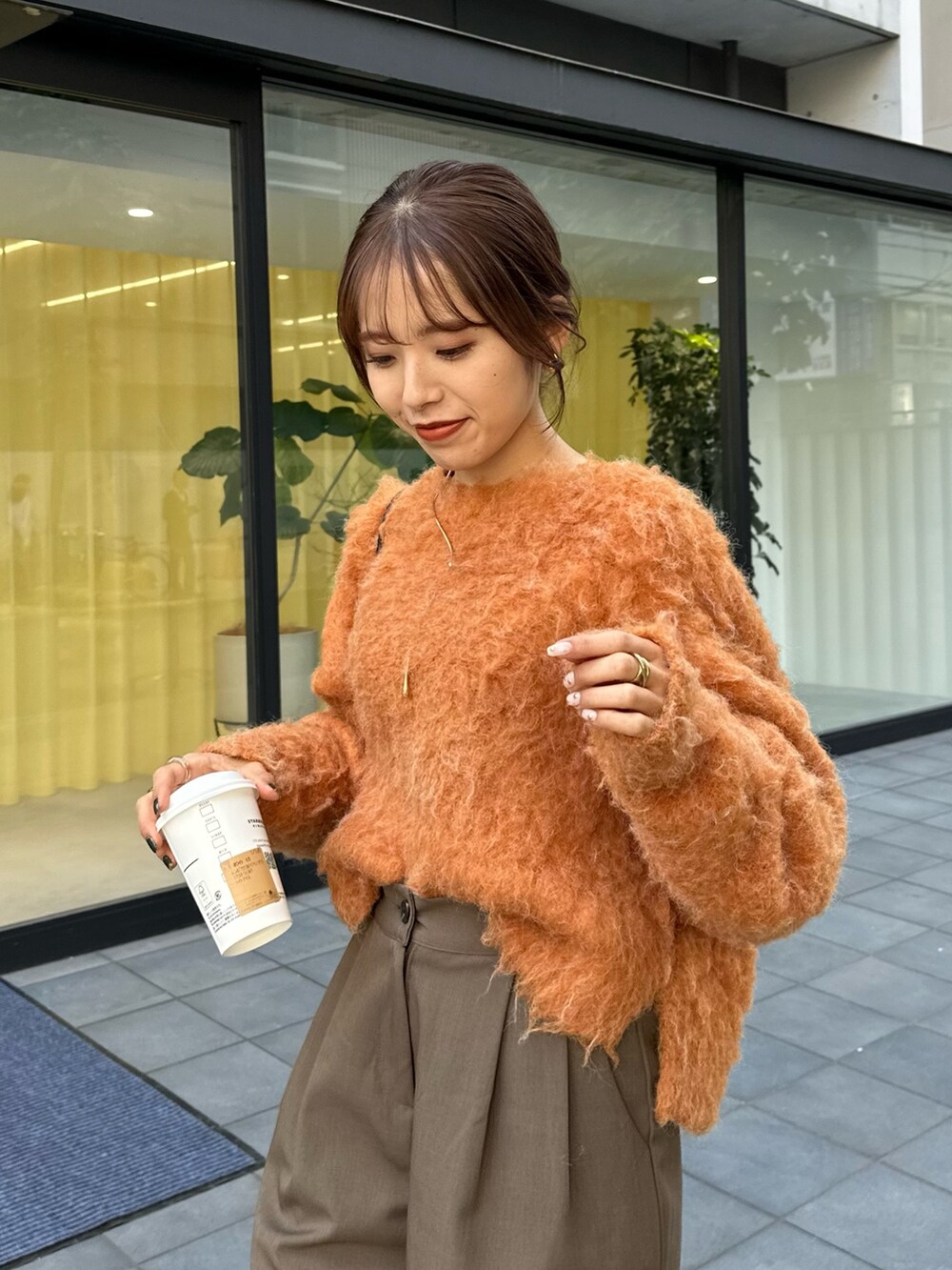 ブラック系のブーツ、オレンジ系のニット/セーター、グリーン系のその他パンツを着用したレディースの秋コーディネートの2枚目の写真