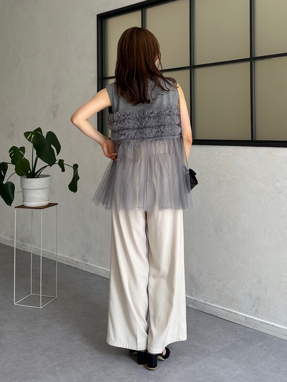 グレー系のTシャツ/カットソー、ホワイト系のスラックス、ブラック系のサンダルを着用したレディースの春コーディネートの3枚目の写真
