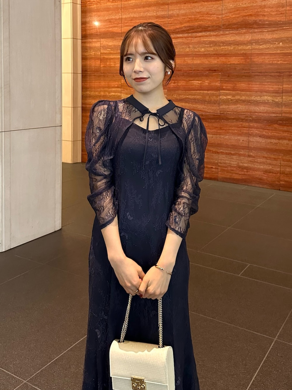 ブルー系のドレス、ベージュ系のパンプス、ベージュ系のハンドバッグを着用したレディースの冬コーディネートの2枚目の写真