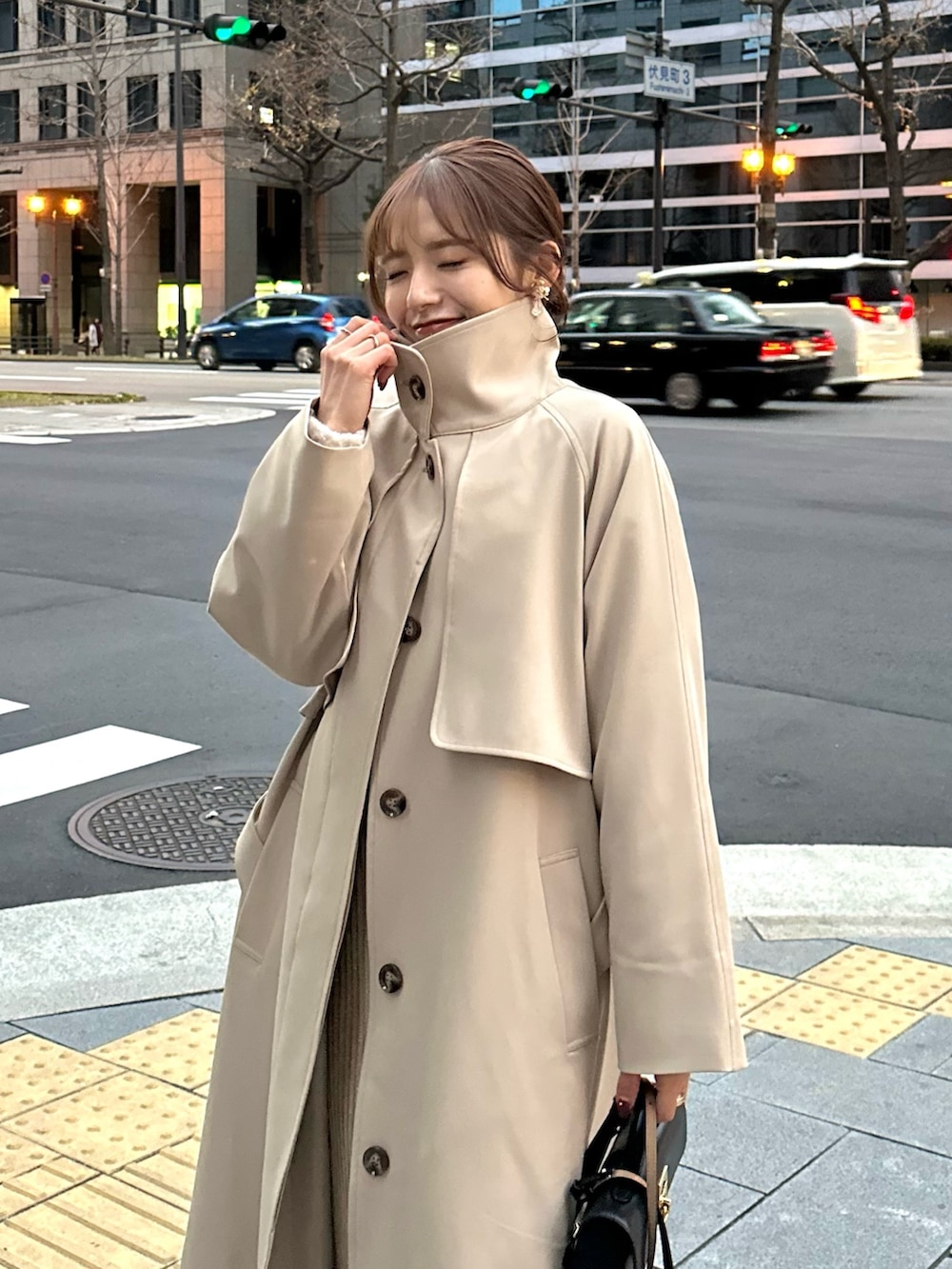 ベージュ系のステンカラーコート、ベージュ系のニット/セーター、ベージュ系のスカートを着用したレディースの冬コーディネートの3枚目の写真