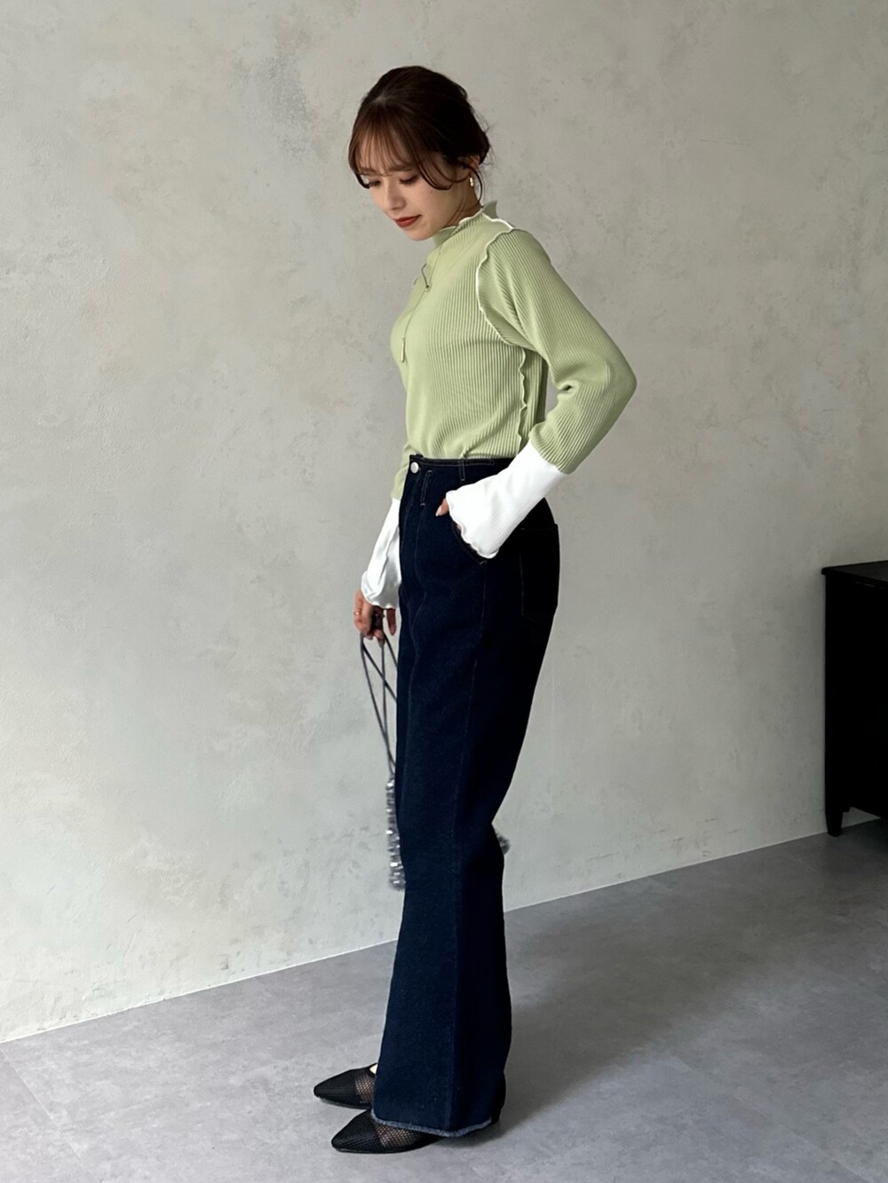 ブルー系のデニムパンツ、グレー系のトートバッグ、グリーン系のTシャツ/カットソーを着用したレディースの冬コーディネートの2枚目の写真