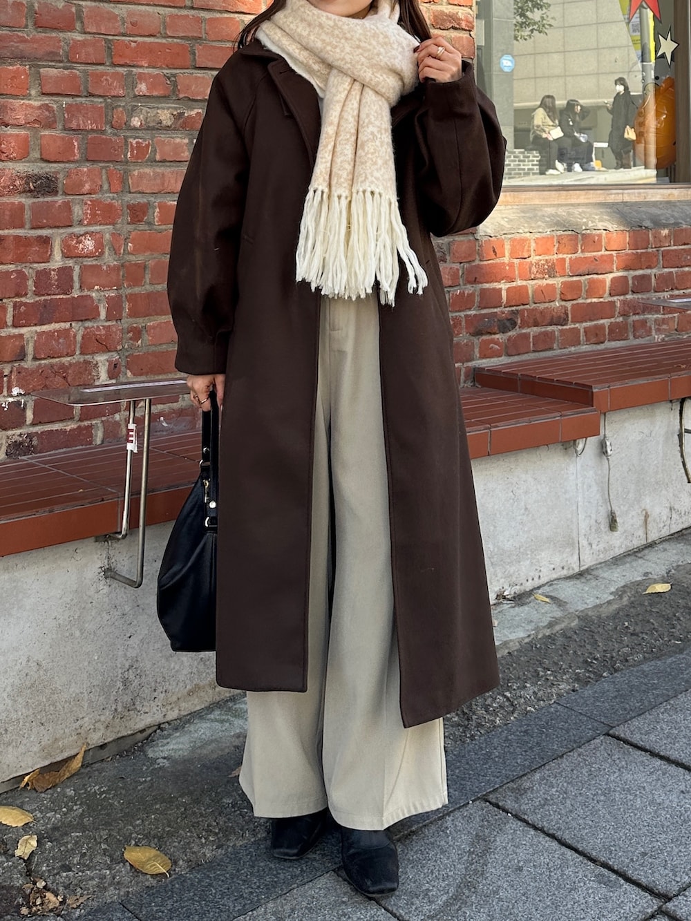 ブラウン系のその他アウター、ベージュ系のスラックス、ホワイト系のニット/セーターを着用したレディースの冬コーディネートの3枚目の写真