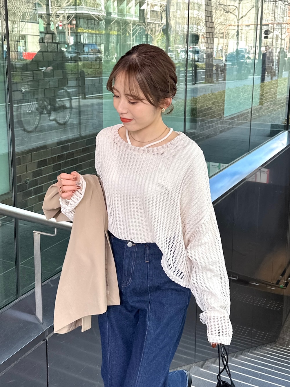 ブルー系のデニムパンツ、ブラック系のトートバッグ、ブラウン系のテーラードジャケットを着用したレディースの春コーディネートの2枚目の写真