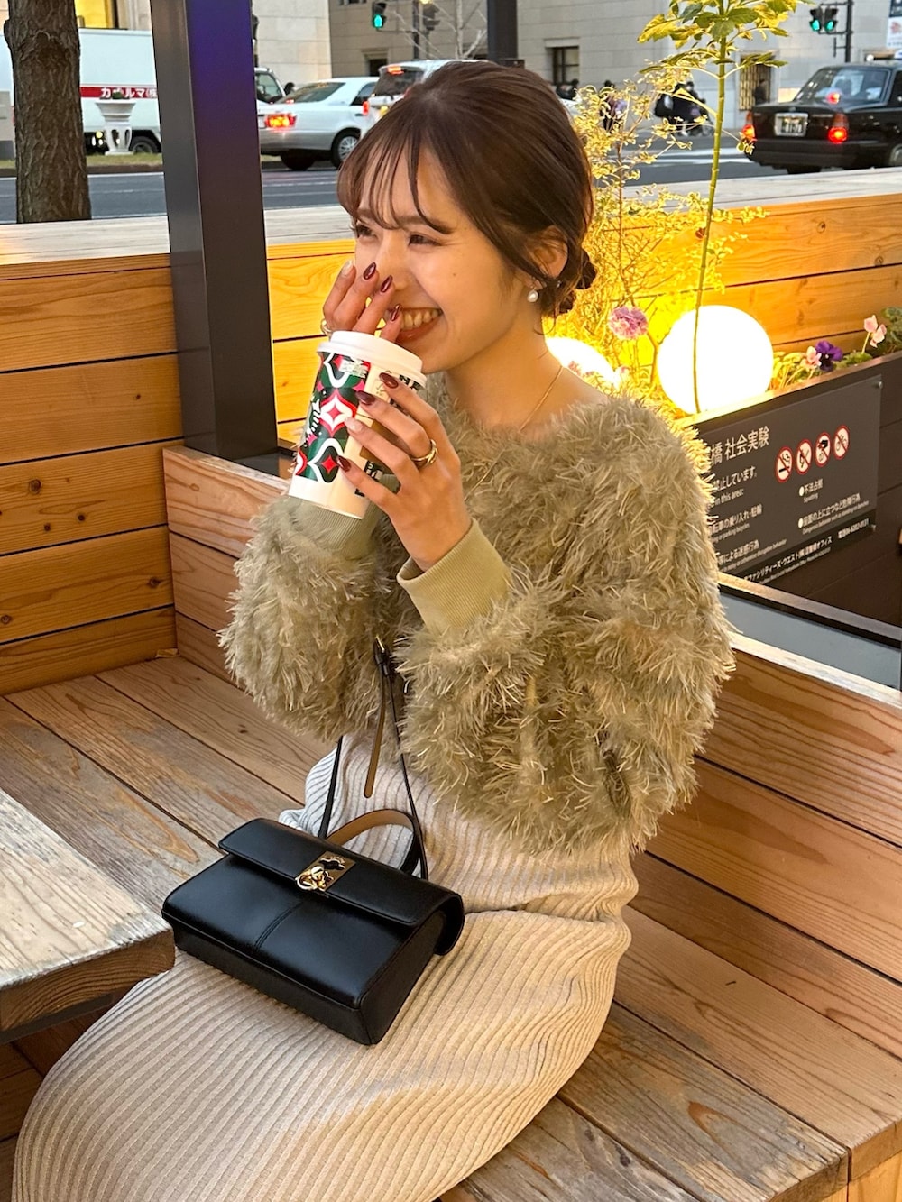 グレー系のスカート、グリーン系のTシャツ/カットソー、ブラック系のステンカラーコートを着用したレディースの冬コーディネートの6枚目の写真