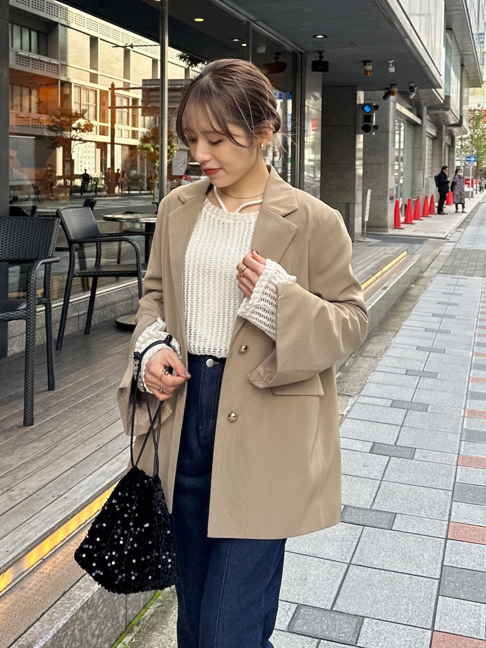 ブルー系のデニムパンツ、ブラック系のトートバッグ、ブラウン系のテーラードジャケットを着用したレディースの春コーディネートの4枚目の写真