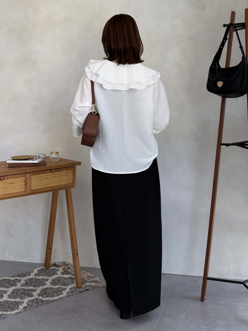 ブラック系のスカート、ブラウン系のショルダーバッグ、ホワイト系のシャツ/ブラウスを着用したレディースの冬コーディネートの4枚目の写真