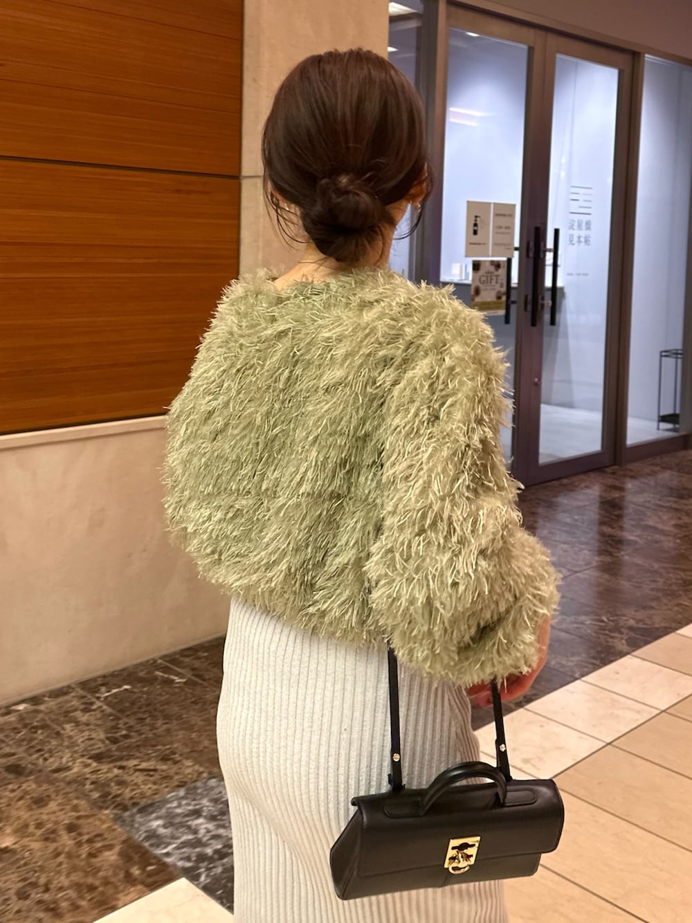 グレー系のスカート、グリーン系のTシャツ/カットソー、ブラック系のステンカラーコートを着用したレディースの冬コーディネートの5枚目の写真