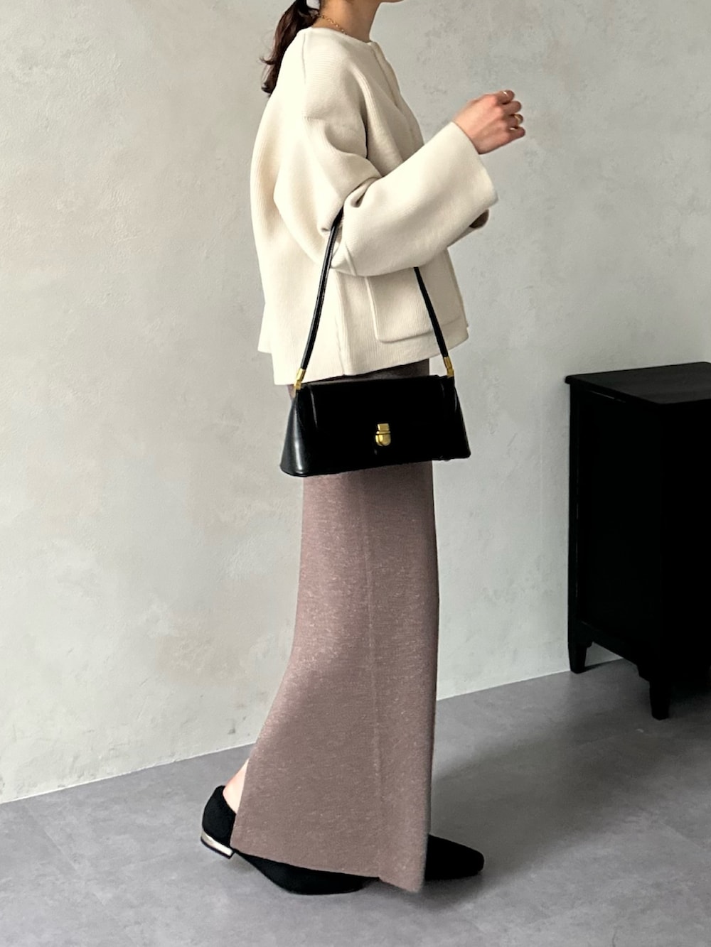 ブラウン系のスカート、ブラック系のパンプス、ホワイト系のカーディガン/ボレロを着用したレディースの冬コーディネートの3枚目の写真