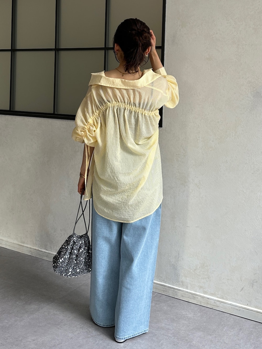 ブルー系のデニムパンツ、シルバー系のパンプス、イエロー系のシャツ/ブラウスを着用したレディースの春コーディネートの4枚目の写真