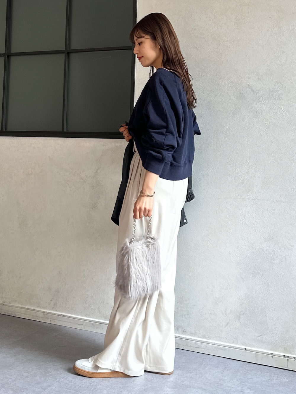 ブルー系のTシャツ/カットソー、ホワイト系のスラックス、ベージュ系のショルダーバッグを着用したレディースの冬コーディネートの3枚目の写真