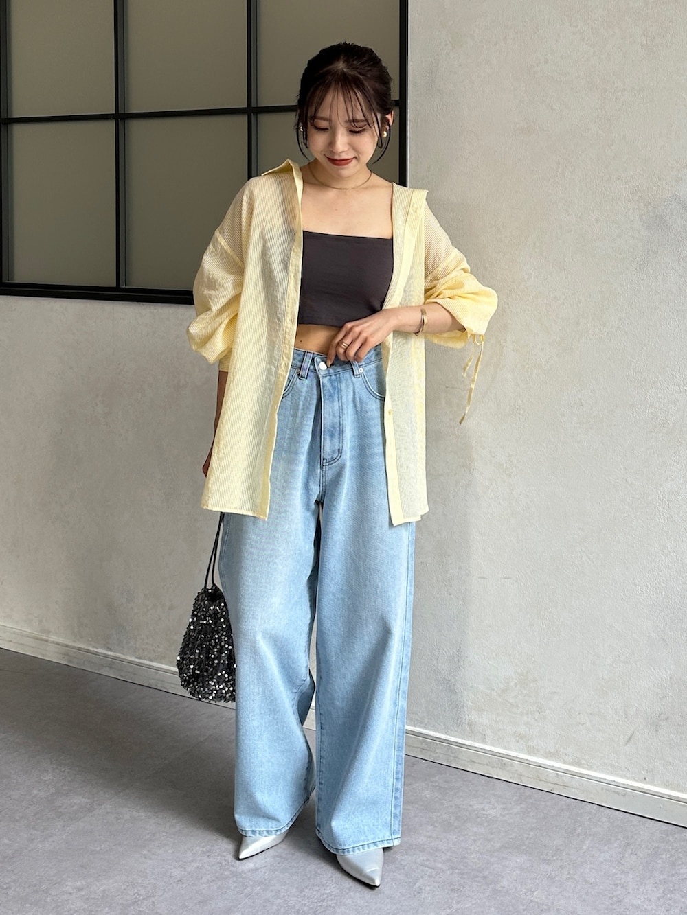 ブルー系のデニムパンツ、シルバー系のパンプス、イエロー系のシャツ/ブラウスを着用したレディースの春コーディネートの2枚目の写真