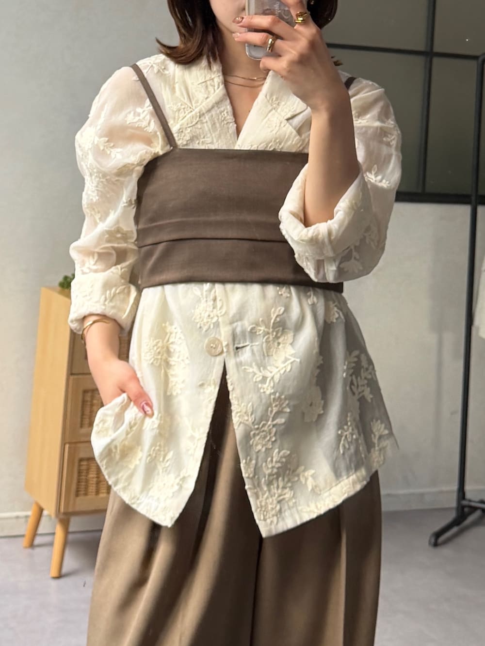 ブラウン系のスラックス、ブラック系のパンプス、ホワイト系のテーラードジャケットを着用したレディースの春コーディネートの5枚目の写真