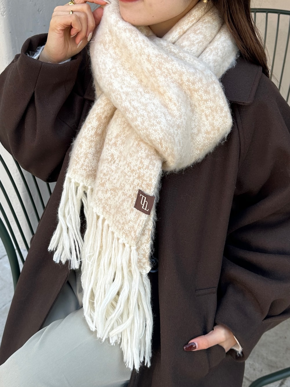 ブラウン系のその他アウター、ベージュ系のスラックス、ホワイト系のニット/セーターを着用したレディースの冬コーディネートの8枚目の写真