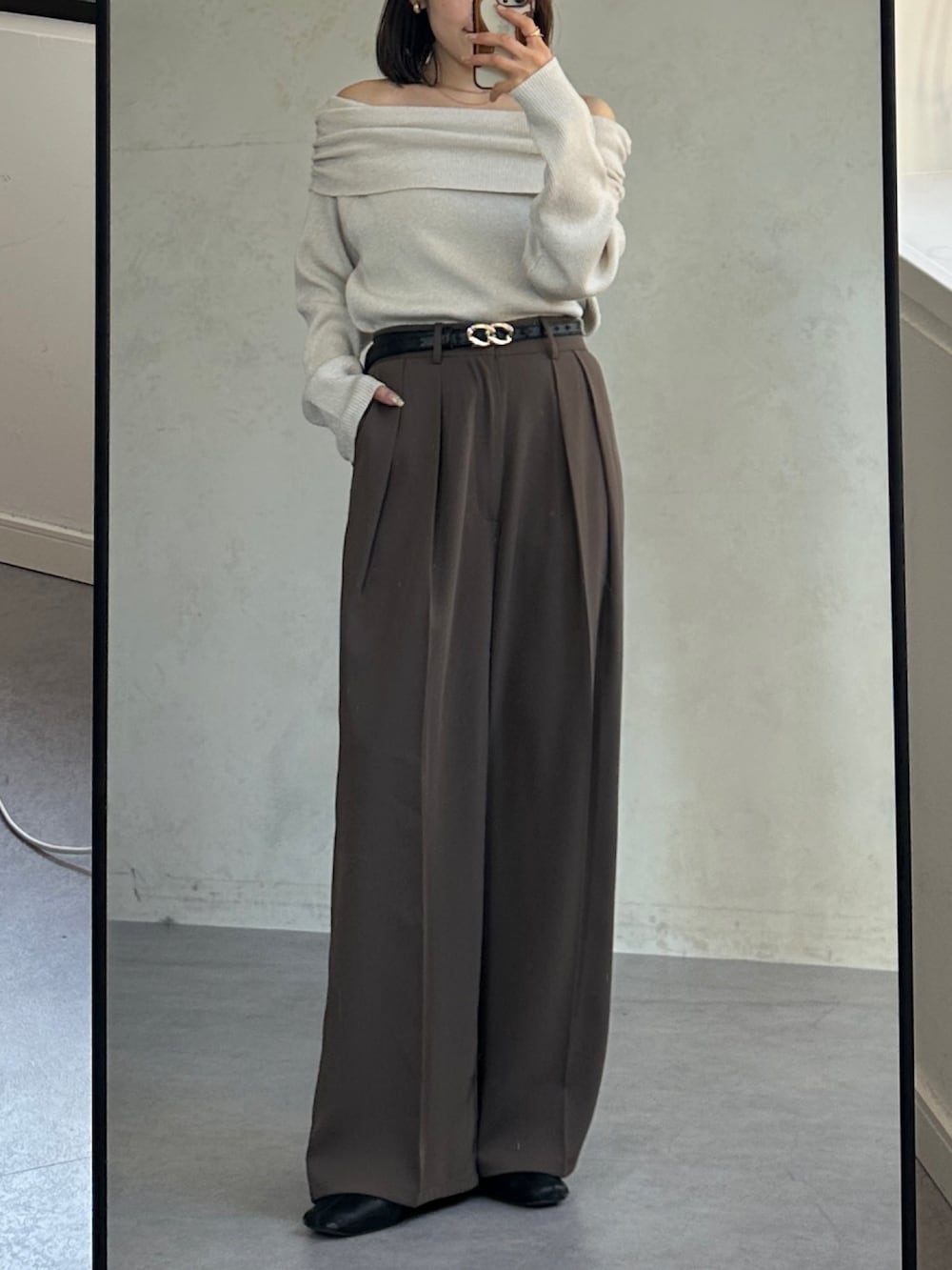 ブラウン系のスラックス、ベージュ系のニット/セーター、ベージュ系のトートバッグを着用したレディースの冬コーディネートの3枚目の写真